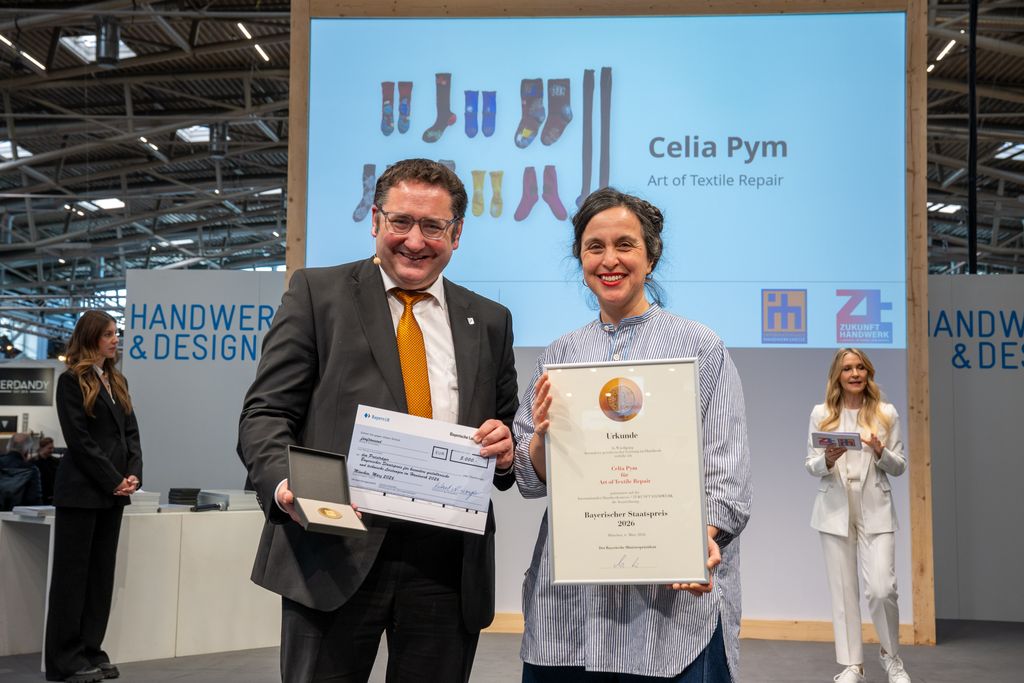 Bayerns Wirtschaftsstaatssekretär Tobias Gotthardt übergibt den Staatspreis an Celia Pym.
