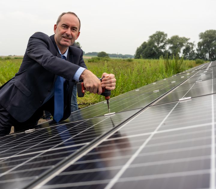 Bayerns Wirtschafts- und Energieminister Hubert Aiwanger montiert das letzte PV-Modul im Solarpark Schornhof.