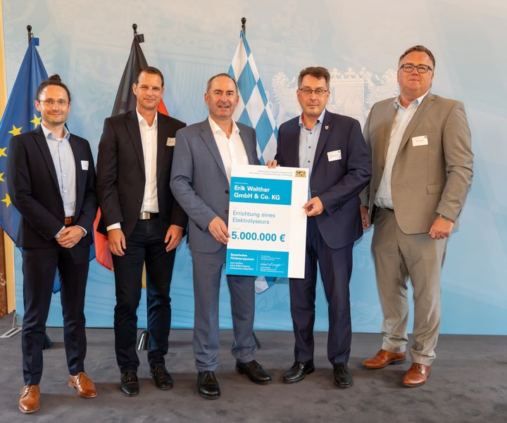 Nikolai Höfling, Firma Erik Walther GmbH (2.v.l.) nimmt gemeinsam mit Uffenheims 1. Bürgermeister, Wolfgang Lampe (4.v.l.) und den Vertretern der Stadtwerke Uffenheim, Sebastian Bittl (1.v.l.) sowie Martin Stellwag (Geschäftsführer, 5.v.l.) den Förderbescheid für den Bau eines Elektrolyseurs entgegen.
Foto: StMWi/E. Neureuther