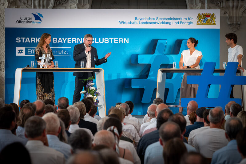 Podiumsdiskussion mit Dr. Stephanie Kauf-Schraml (Sprecherin des Clusters Umwelttechnologie; SCHRAML GmbH), Ulrich Huggenberger (XITASO), Dr. Lena Stern (OHB) und Prof. Dr. Dr. Fabian Theis (Vorsitzender des Bayerischen KI-Rats, Helmholtz Zentrum München). Foto: StMWi/A. Heddergott