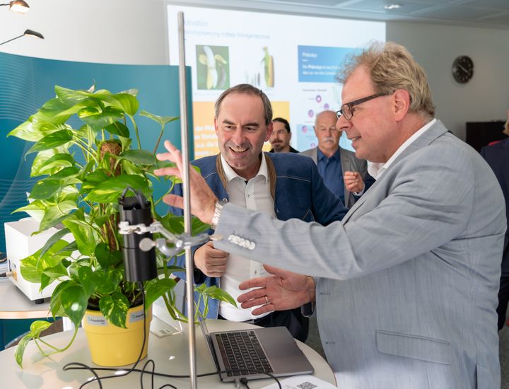 Dr. Frank Ansorge, wissenschaftlicher Mitarbeiter am Fraunhofer EMFT, erklärt Bayerns Wirtschaftsminister Hubert Aiwanger die entwickelte Sensortechnologie für Pflanzen. (Foto: StMWi / E. Neureuther)