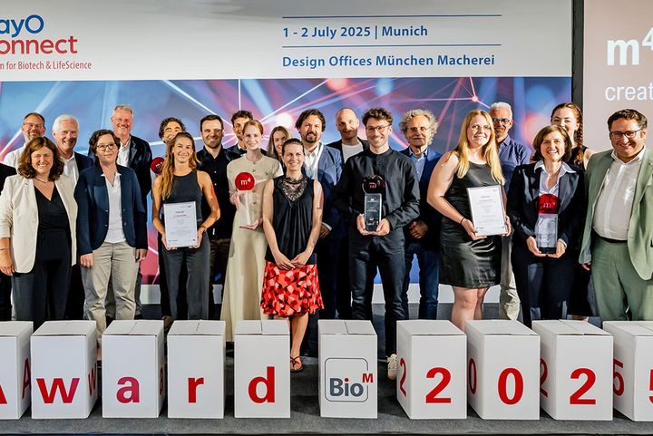 Das Bild zeigt ein Gruppenfoto: die Gewinner-Teams des m4 Award 2025 bei der Preisverleihung am 2. Juli 2025 zusammen mit Bayerns Wirtschaftsstaatssekretär Tobias Gotthardt (ganz rechts) im Rahmen der BioM Konferenz BayOConnect (© BioM/Bert Willer).