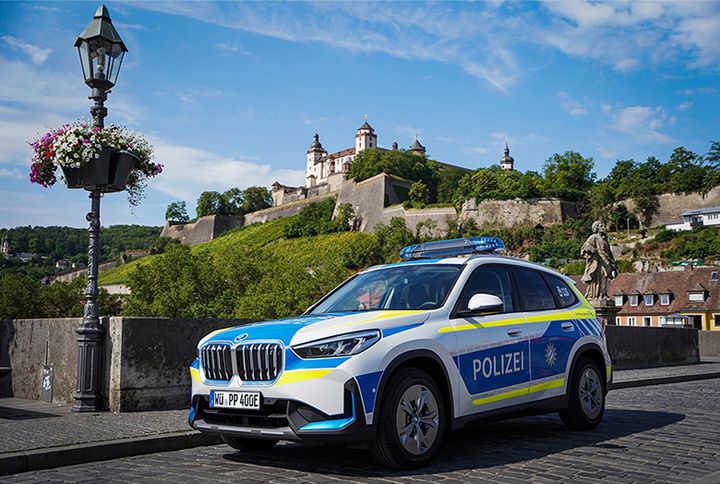 Ein Polizeiauto steht auf einer Brücke vor einer Burg.
