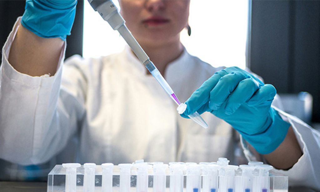 Eine Wissenschaftlerin pipettiert eine Flüssigkeit. 