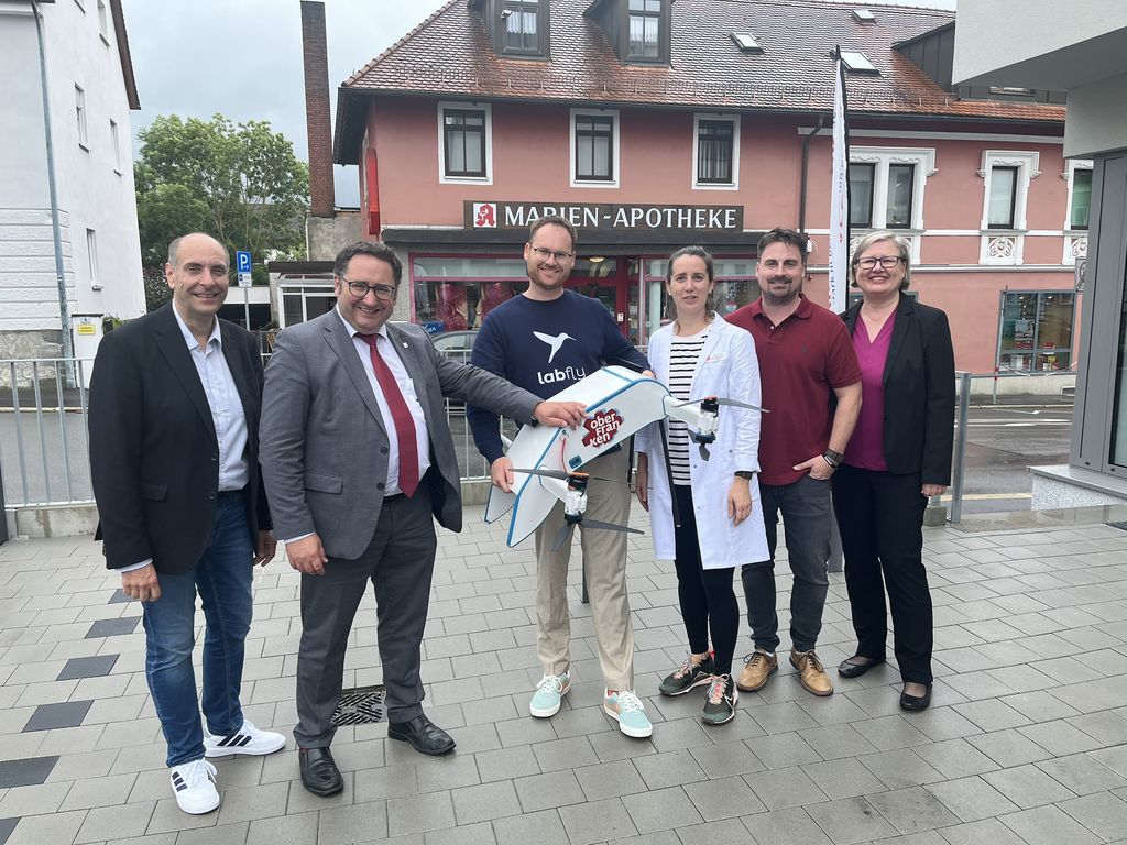 Matthias Fischer (Projektleitung Oberfranken Offensiv) Tobias Gotthardt (Staatssekretär im Bayerischen Staatsministerium für Wirtschaft, Landesentwicklung und Energie, Tim Fischer (CEO Labfly), Dr. Sarah Seiberth (Apothekerin Stadt Apotheke Wunsiedel), Dr. Dominik Bauer ( Marien Apotheke Marktredwitz), Dr. Alexandra Schmidt Buchholz (Stv. Referatsleiterin Regionalmanagement und Standortentwicklung StMWi) nach Testflügen in Marktredwitz ©Regionalmarketing Oberfranken Offensiv