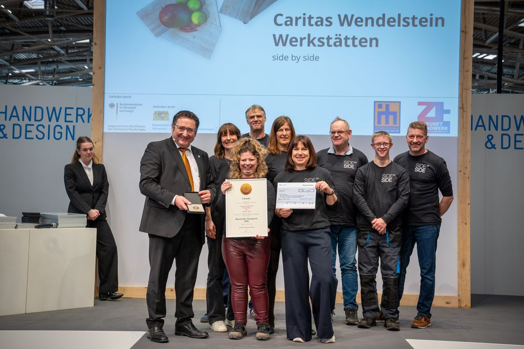 Bayerns Wirtschaftsstaatssekretär Tobias Gotthardt übergibt den Staatspreis an die Wendelstein Werkstätten.