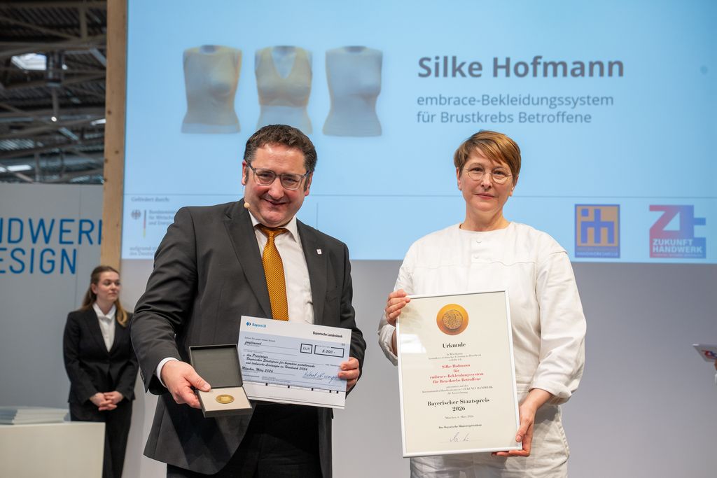 Bayerns Wirtschaftsstaatssekretär Tobias Gotthardt übergibt den Staatspreis an Silke Hofmann.