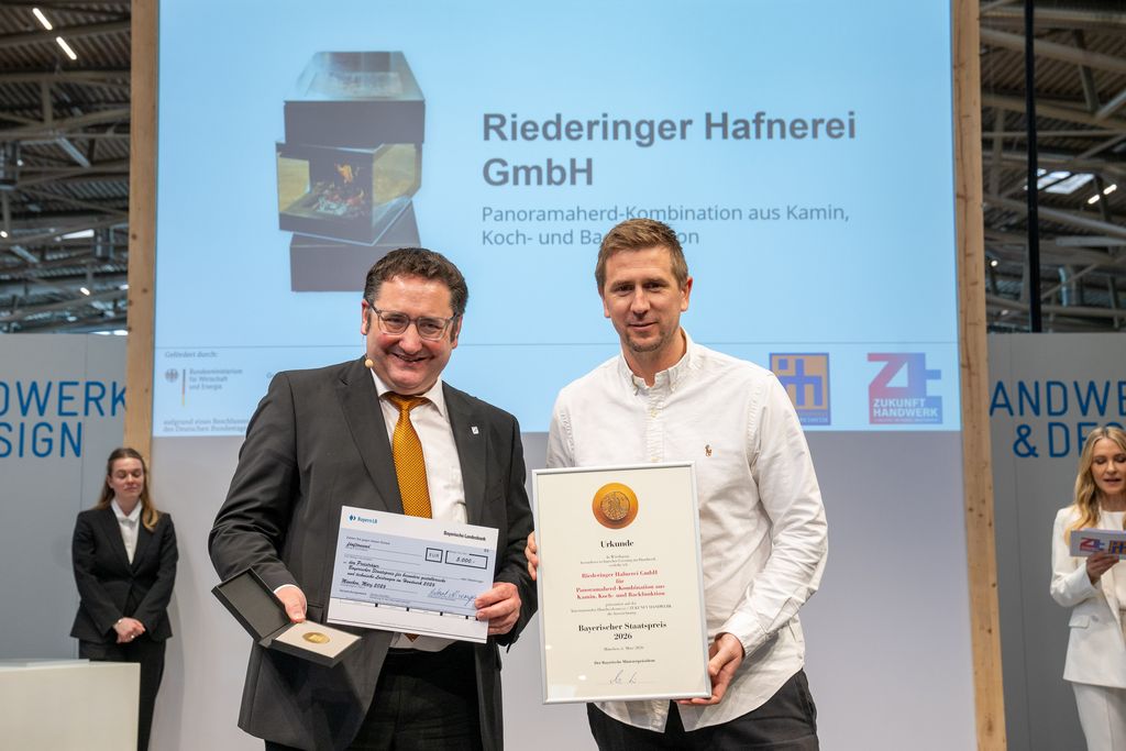 Bayerns Wirtschaftsstaatssekretär Tobias Gotthardt übergibt den Staatspreis an die Riederinger Hafnerei GmbH.