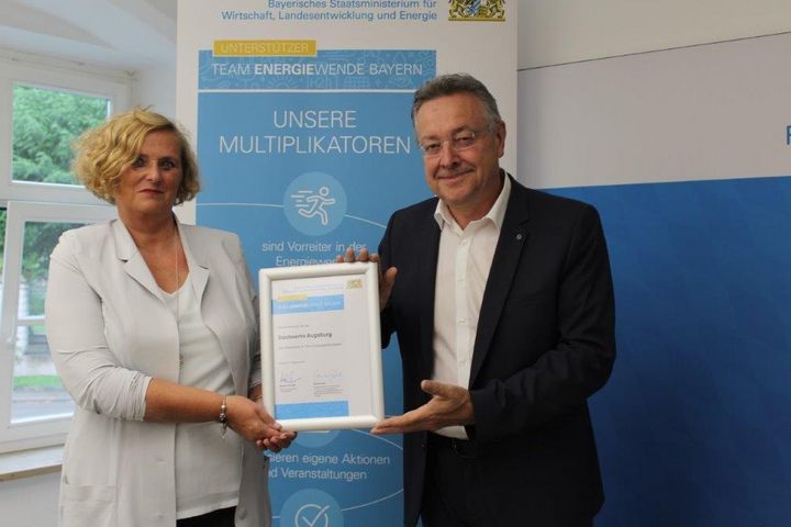 Frau Regierungspräsidentin Barbara Schretter überreicht Herrn Anton Asam von den Stadtwerken Augsburg die Ernennungsurkunde.