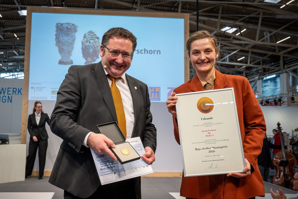 Bayerns Wirtschaftsstaatssekretär Tobias Gotthardt übergibt den Staatspreis an Sarah Pschorn.