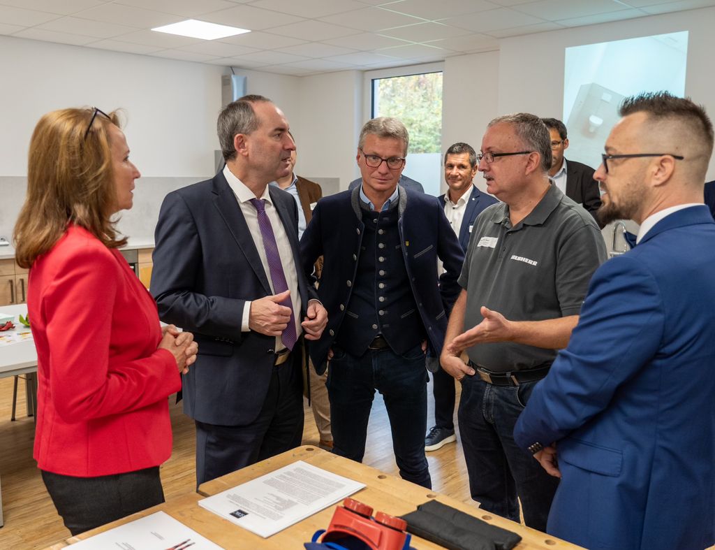 Alexander Maier (Ausbilder bei der Firma Liebherr-Components) berichtet Wirtschaftsminister Aiwanger über seine langjährige Zusammenarbeit mit dem bfz bei der Ausbildungsförderung. Foto v. l. n. r.: Ingrid Schmidt (bfz-Leiterin Landshut), Staatsminister Aiwanger, Landrat Bernd Sibler (Lkr. Deggendorf), Alexander Maier, Sebastian Süß (bfz-Seminarleiter). (Foto: StMWi / E. Neureuther)