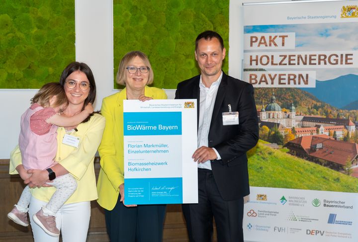 Amtschefin Dr. Sabine Jarothe (Mitte) hat im Wirtschaftsministerium einige Projektinitiativen, die über das Förderprogramm &quot;BioWärme Bayern&quot; gefördert werden, besonders gewürdigt. Die Projektverantwortlichen Florian und Marina Markmüller mit Tochter nahmen die Förderurkunde entgegen. Foto: StMWi/Bastian Brummer