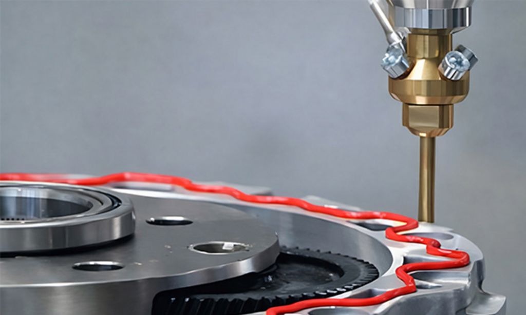 Eine Düse spritzt roten Klebstoff auf ein silbernes Metallteil