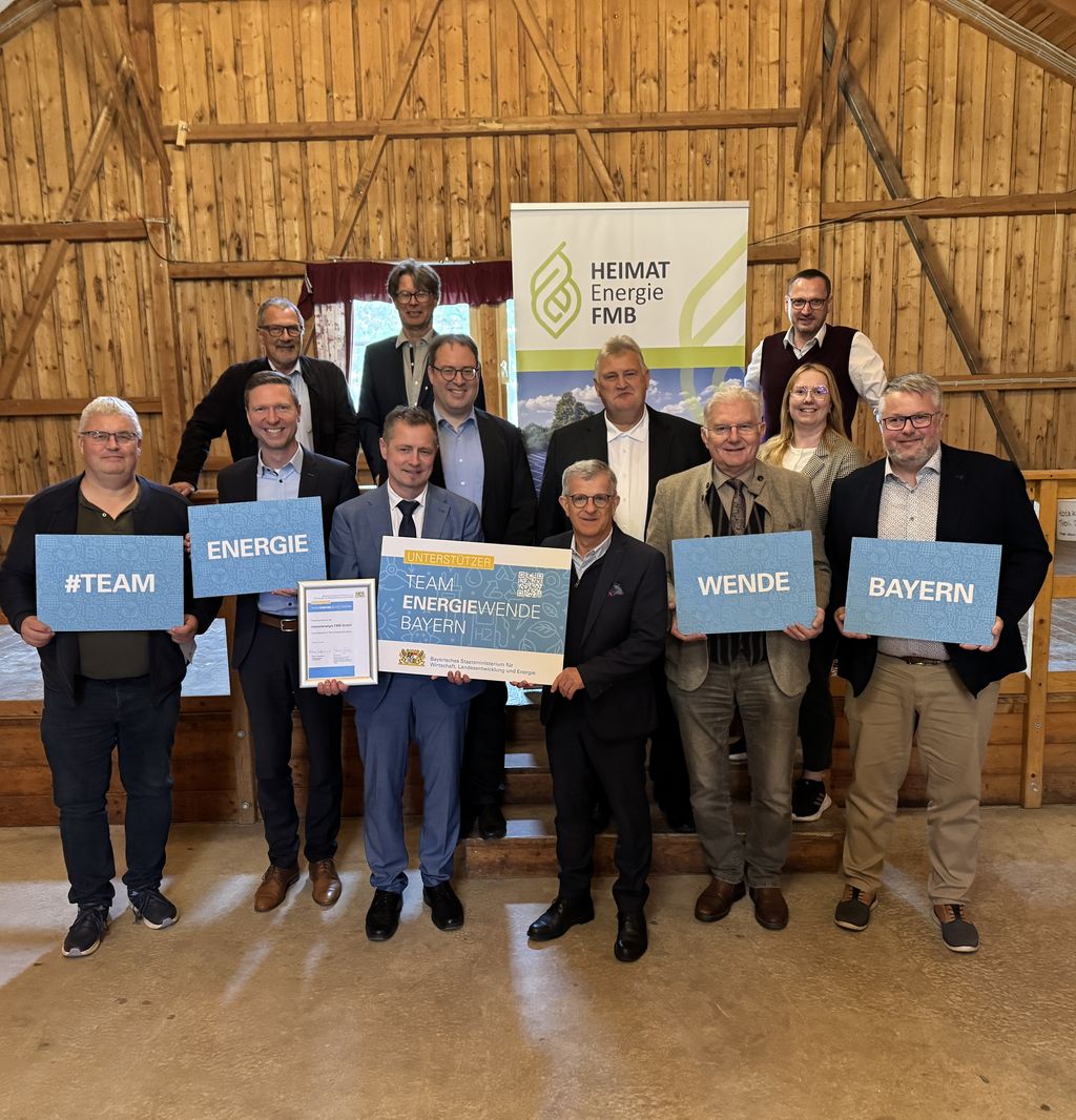 Ein Gruppenbild mit Personen, die Schilder des Teams Energiewende Bayern in die Kamera halten. Darunter Regierungspräsident Florian Luderschmid und  Vertreterinnen und Vertreter der Heimatenergie FMB GmbH.
