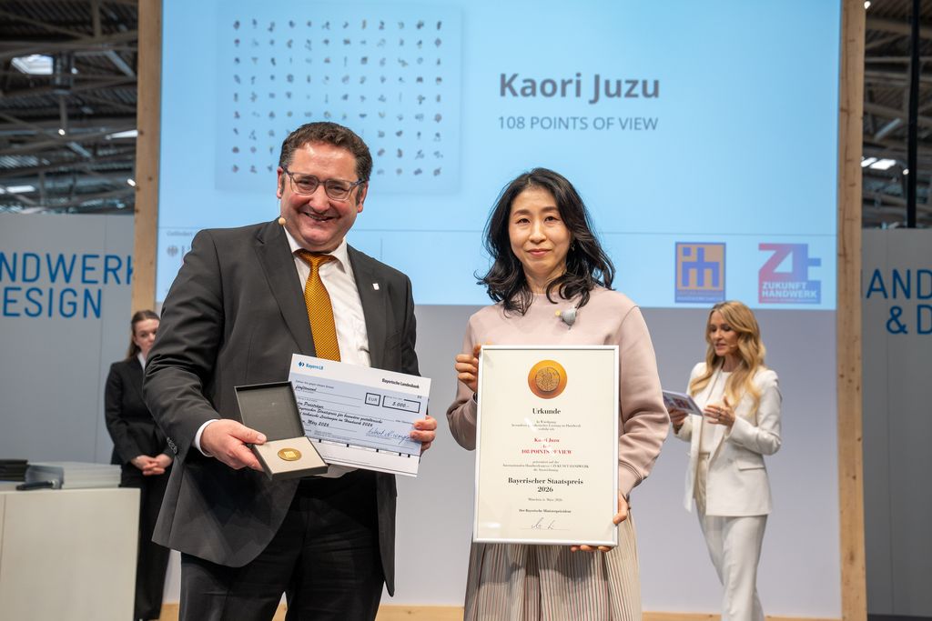 Bayerns Wirtschaftsstaatssekretär Tobias Gotthardt übergibt den Staatspreis an Kaori Juzu.