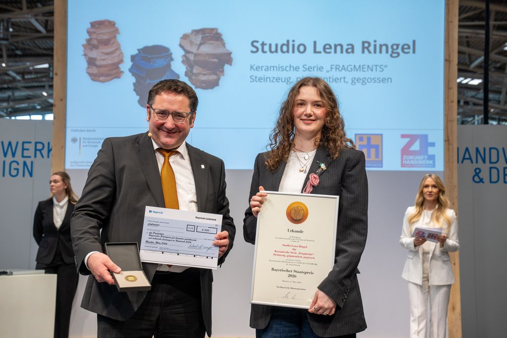 Bayerns Wirtschaftsstaatssekretär Tobias Gotthardt übergibt den Staatspreis an Lena Ringel.