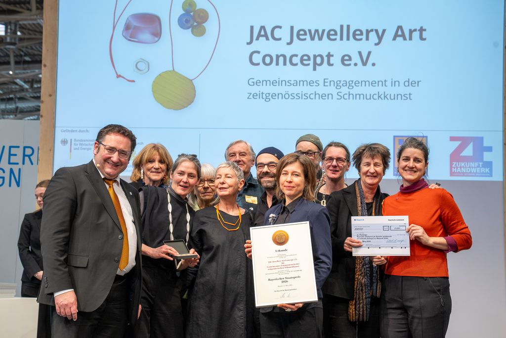 Bayerns Wirtschaftsstaatssekretär Tobias Gotthardt übergibt den Staatspreis an JAC Jewellery Art Concept e.V..