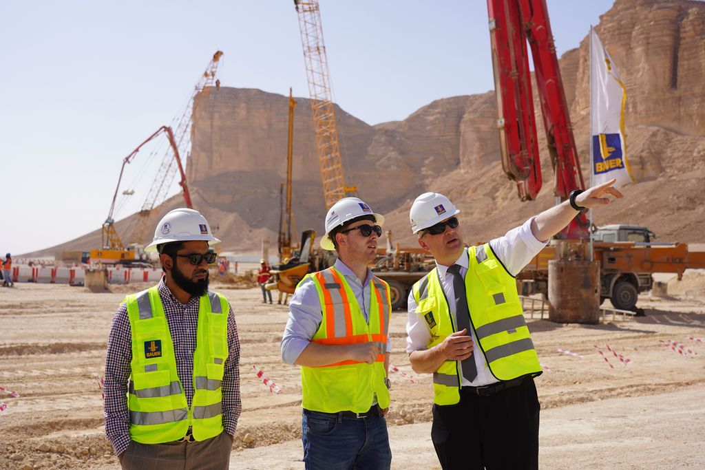 Staatssekretär Roland Weigert (rechts) hat sich bei Stefan Neidhart (Mitte), Projektmanager der BAUER Spezialtiefbau GmbH, über ein Projekt in der Nähe von Riad informiert. Das Schrobenhausener Spezialtiefbauunternehmen errichtet dort die Gründungselemente für eine Weltrekord-Achterbahn, die Teil des prestigeträchtigen Tourismusprojektes Qiddiya sein wird. Foto: StMWi/Assenbrunner