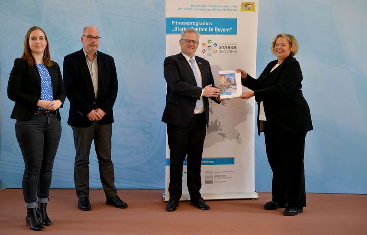 Ministerialdirektorin Dr. Ulrike Wolf überreicht dem Team aus Schwandorf das Handbuch.