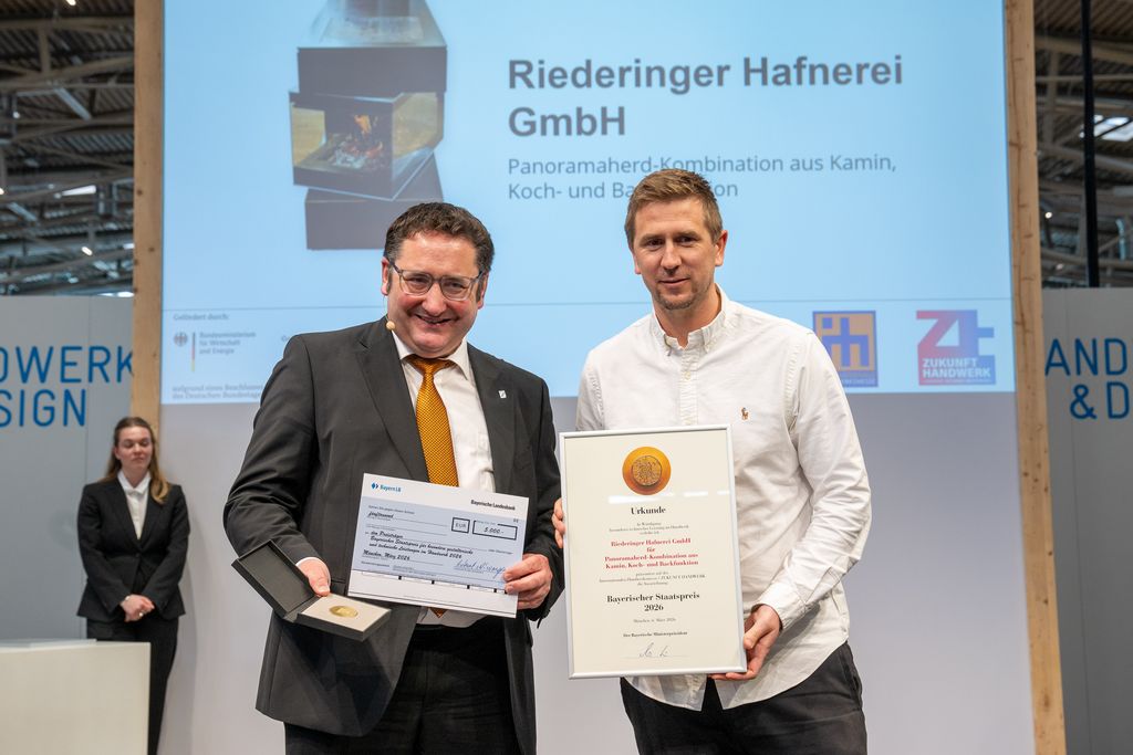 Bayerns Wirtschaftsstaatssekretär Tobias Gotthardt übergibt den Staatspreis an die Riederinger Hafnerei GmbH.
