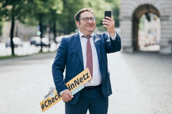 Staatssekretär Tobias Gotthardt hält ein Smartphone in der Hand.