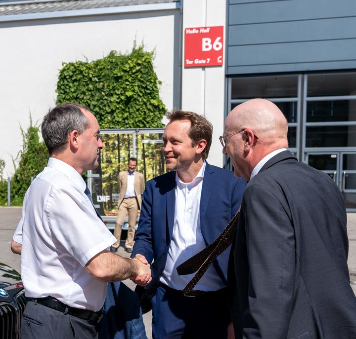Wirtschaftsminister Hubert Aiwanger (links) wird von den beiden Geschäftsführern Dr. Reinhard Pfeiffer (rechts) und Stefan Rummel (mitte) der Messe München begrüßt 