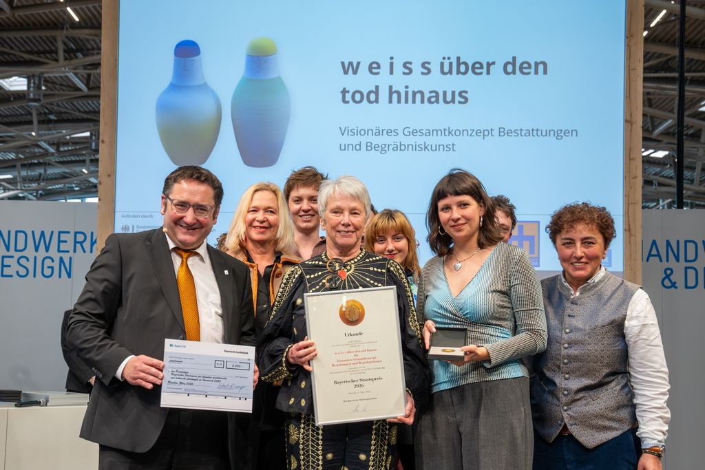 Bayerns Wirtschaftsstaatssekretär Tobias Gotthardt übergibt den Staatspreis an 'w e i s s über den tod hinaus -Bestattungen und Begräbniskunst'.